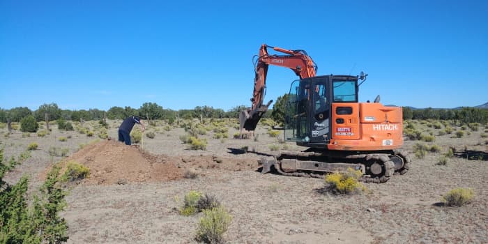 An excavator digs site test holes—deep, sloping trenches, actually—on our property in the area we preferred to build.
