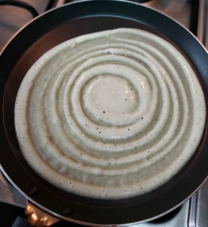 Pour a ladleful of batter in the center of the pan. Gently spread the batter in a circular motion, forming a thin dosa.