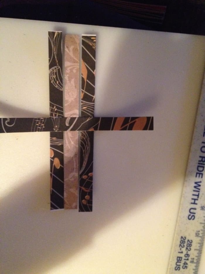 Add one strip on either side of the first one. The middle one should be under the horizontal strip. The side ones should be on top of the horizontal strip.
