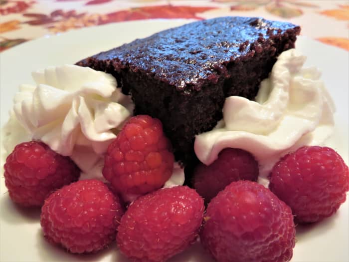 Piece of chocolate mayonnaise cake served with ReddiWip and fresh raspberries