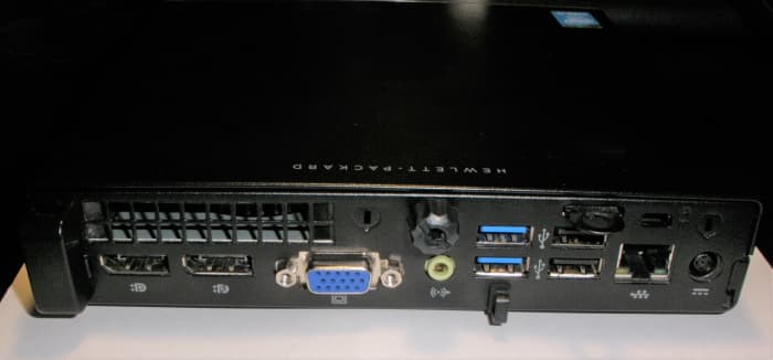 The rear of an HP ProDesk 600 G1 DM. Unplug the power adapter and all peripherals before opening it to service. The cover is secured by the single thumb-screw at the rear-center of the PC.