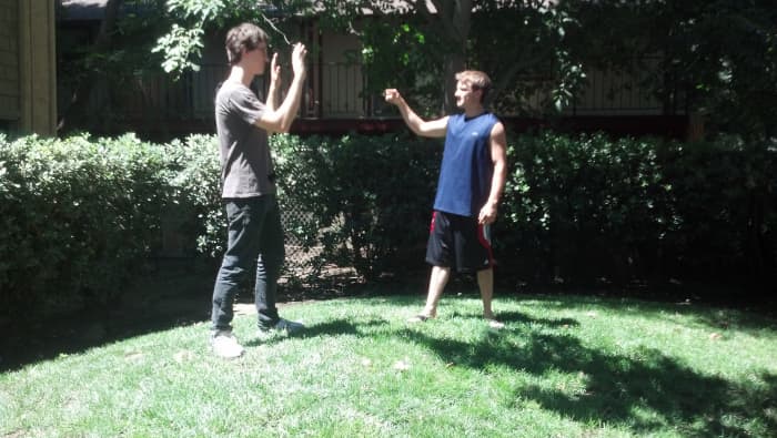 A steps back with his right foot and raises his hands, preparing for the possibility of an attack from B.