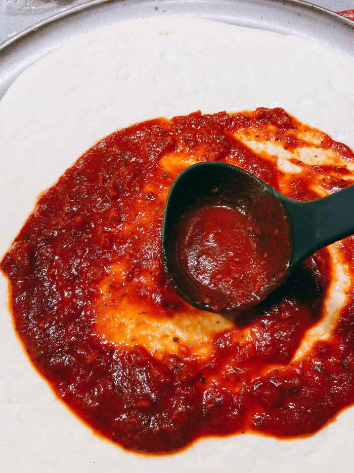 Use a spatula to spread the sauce evenly on the dough.