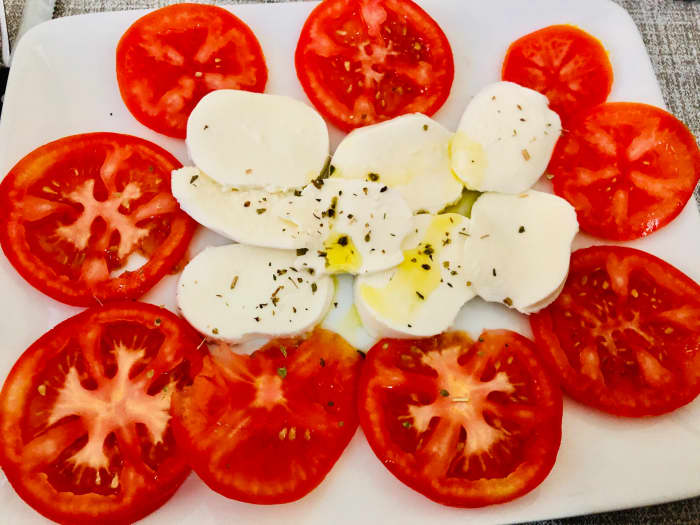 A Caprese salad, which is a popular Italian dish composed of tomatoes and slices of mozzarella. Mozzarella in Italy is shaped like a balloon; it retains liquid and tastes very fresh.