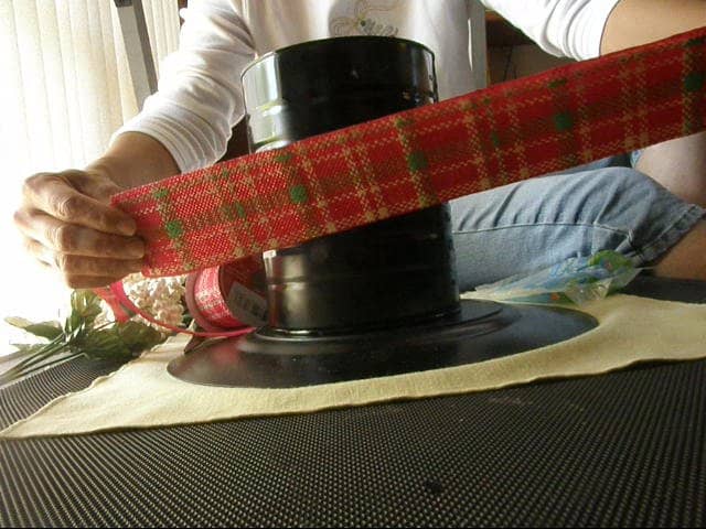Cut two strips of ribbon that will be attached to the top of the can as well as the bottom, as shown in the next photograph. Make sure to cut about a 1/4 inch extra to overlap.