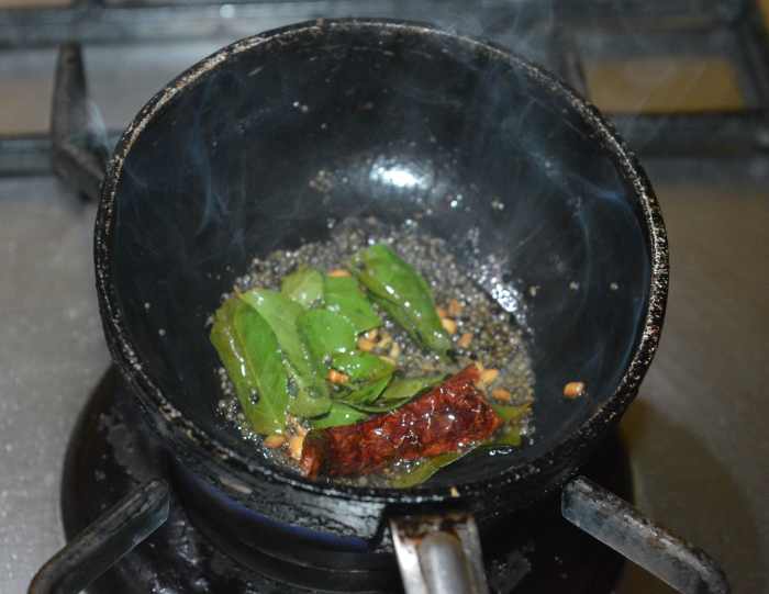 Step three: Make the tempering. Heat ghee or oil in a small pan. Throw in mustard seeds and allow them to crackle. Add white lentils, broken red chili, and curry leaves. When the lentils become golden brown, turn off the heat.