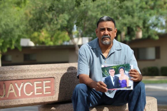 Adrienne Salinas's father Rick sitting at Jaycee Park in Tempe, Ariz., showing a picture of his murdered daughter.