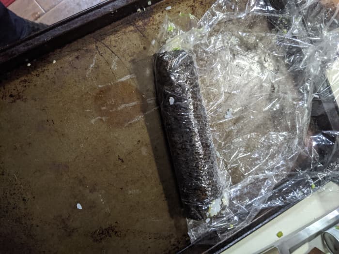 Use plastic to help pull up edge of seaweed. Roll up, make sure it's tight. Remove plastic from top as you roll.