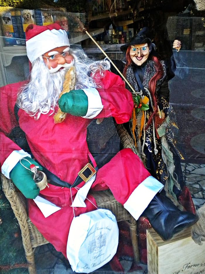 La Befana next to Santa. Store window decoration in Italy.