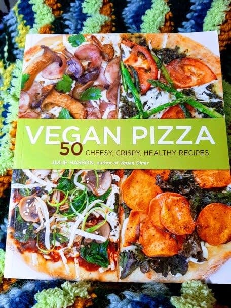 The cover of "Vegan Pizza," by Julie Hasson, propped up against my crocheted blanketed knees.