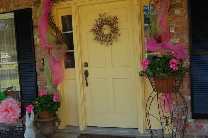 Front Door with Easter Decorations on a Yellow Door with two side planters decorated for the holiday