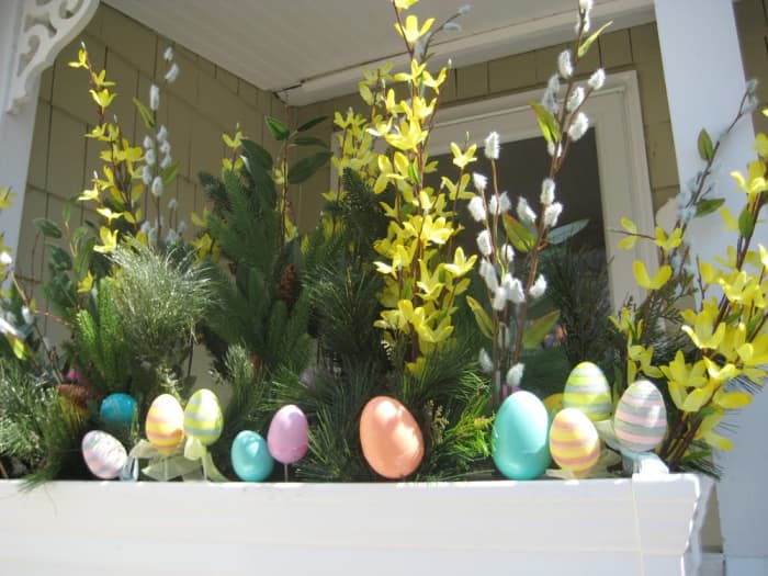 Easter eggs in bright blue, orange yellow and green adorn an exterior porch railing