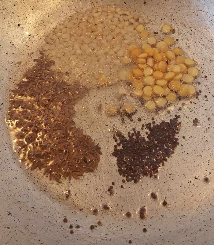 In a pan, heat 1-2 tablespoons of oil. Splutter 1/2 teaspoon of mustard seeds and 1 teaspoon of cumin seeds. Add 1 tablespoon of split black gram (urad dal) and Bengal gram.