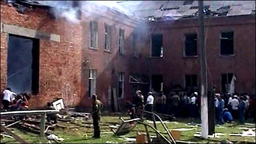 The burning schoolhouse after the siege was lifted, and civilians eagerly awaiting news of their loved ones.