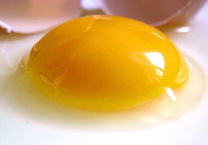 A raw hen's egg with the yolk sitting proud of the white, indicating freshness.