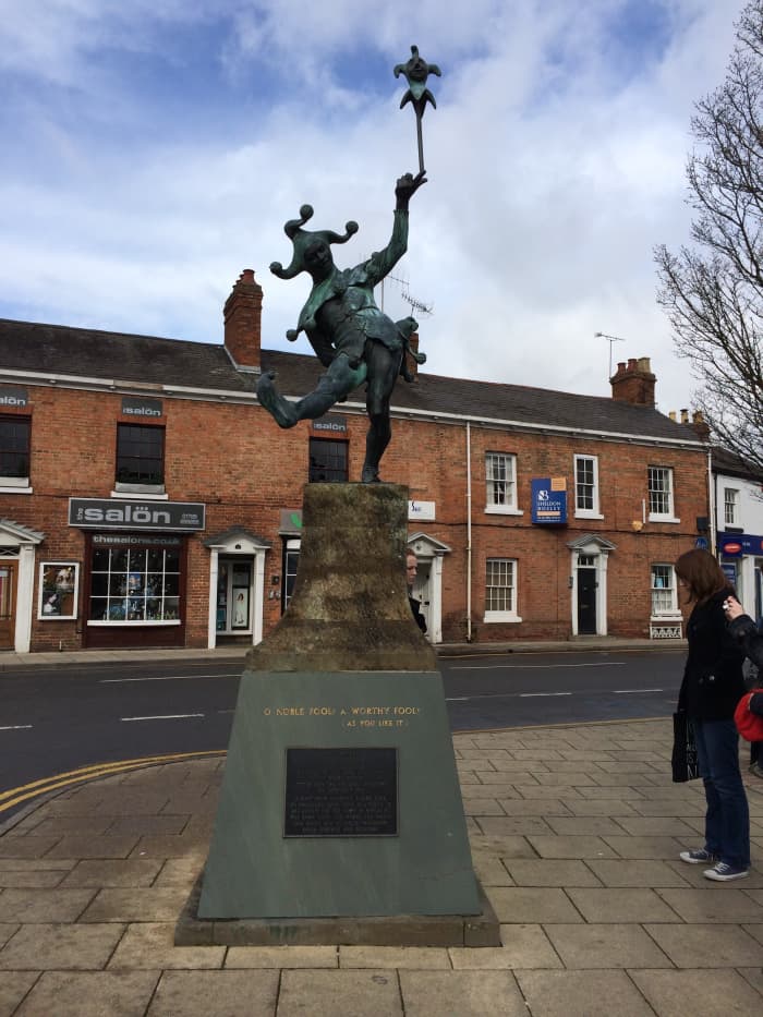 The statue has a quote by Shakespeare that says, "O Noble Fool! A Worthy Fool!" from his play As You Like It