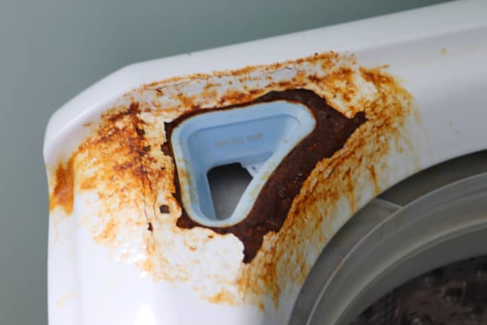 Rust has completely corroded through the metal of this washing machine. Earlier attention to the problem would have prevented the oxidation from destroying the metal. This damage cannot be fixed with sanding and repainting.