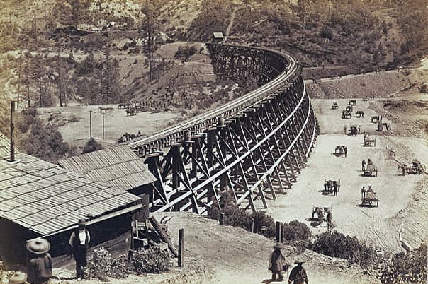 Chinese labourers shifting fill by hand next to a trestle. The fill would eventually replace the bridge.