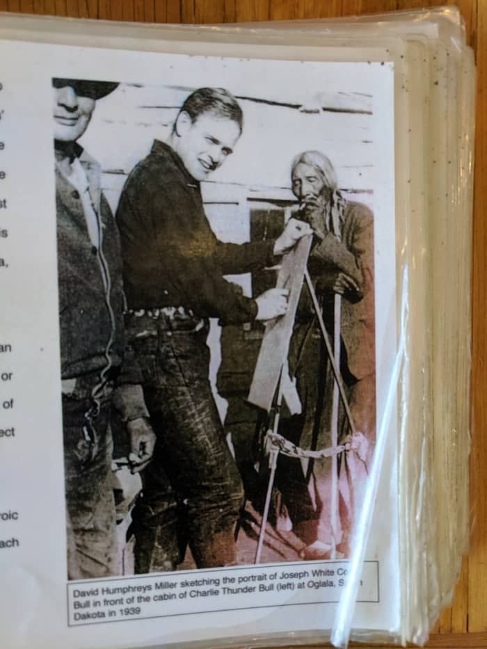 David Humphreys Miller sketching the portrait of Joseph White Co Bull in front of the cabin of Charlie Thunder Bull (to left of Miller) at Oglala, South Dakota in 1939.