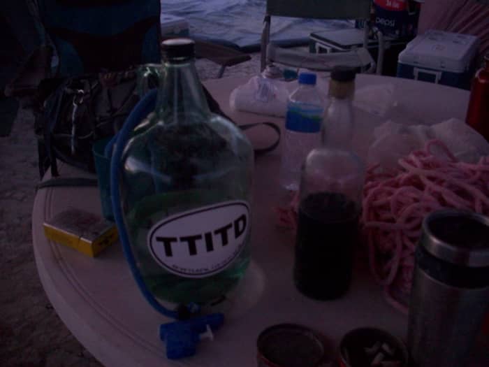 The table at our camp holding all the necessities, backpack, water, cup, booze, rope, cigarettes, bungee cord, and squirt gun.