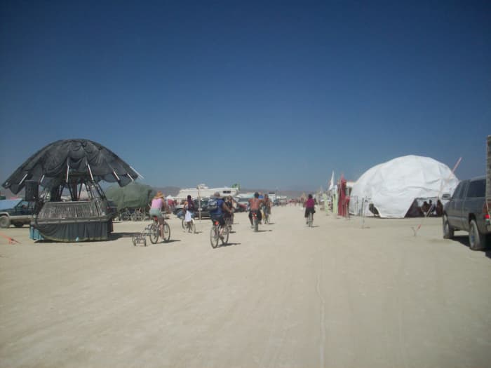 Biking around Black Rock City. Notice someone using a handcart as a trailer to go get ice from Artica.