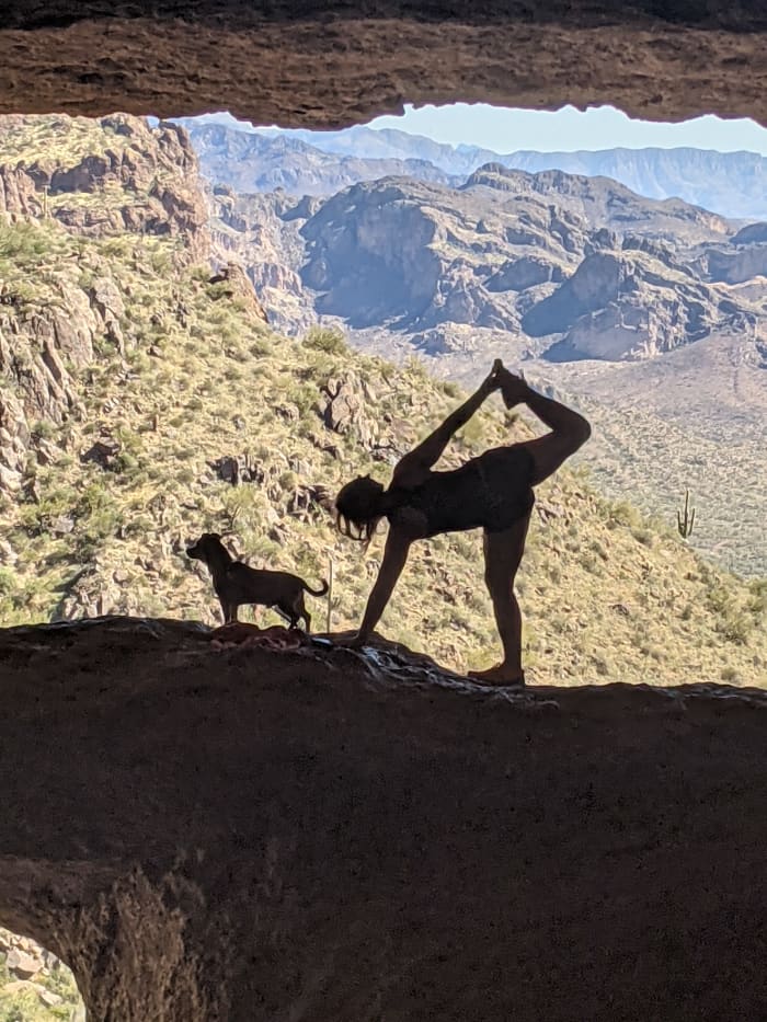 A visitor to Wave Cave doing a yoga position with her dog in the rock across the front of Wave Cave