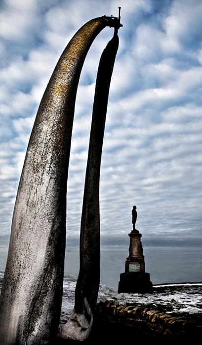 A view of the whalebone arch at Whitby West Cliff with Captain Cook's statue behind, overlooking the harbour these doughty seamen set out from
