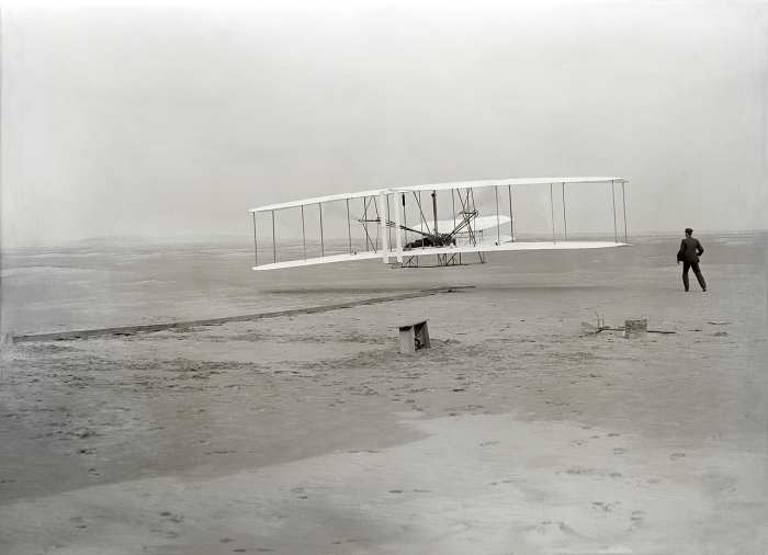 First flight of the Wright Flyer, December 17, 1903, Orville piloting, Wilbur running at wingtip