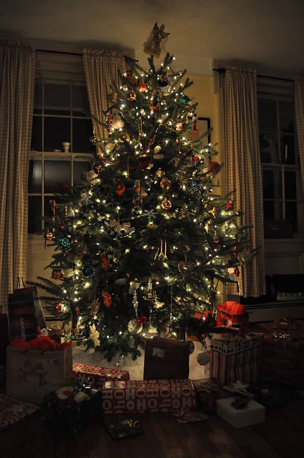 A Christmas tree is lit and decorated, surrounded by presents on Christmas Eve.