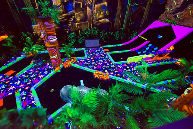 Some mini golf courses are expanding their decor and offering arcades, paintball games, laser tag, and cafes. This one is indoors and features blacklight.