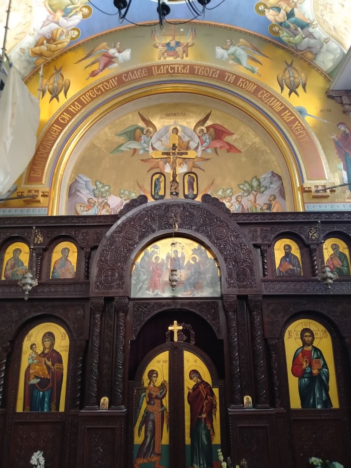 A beautiful, wooden iconostasis with two wings. Usually men light candles on the right and women, on the left hand side of the iconostasis. The gates in the middle represent the doors to heaven. Usually, I see Archangel Michael over the main arc.