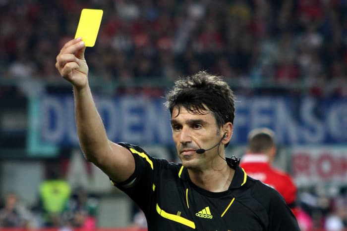 The referee gives out a yellow card as a warning for bad fouls or rulebreaking.