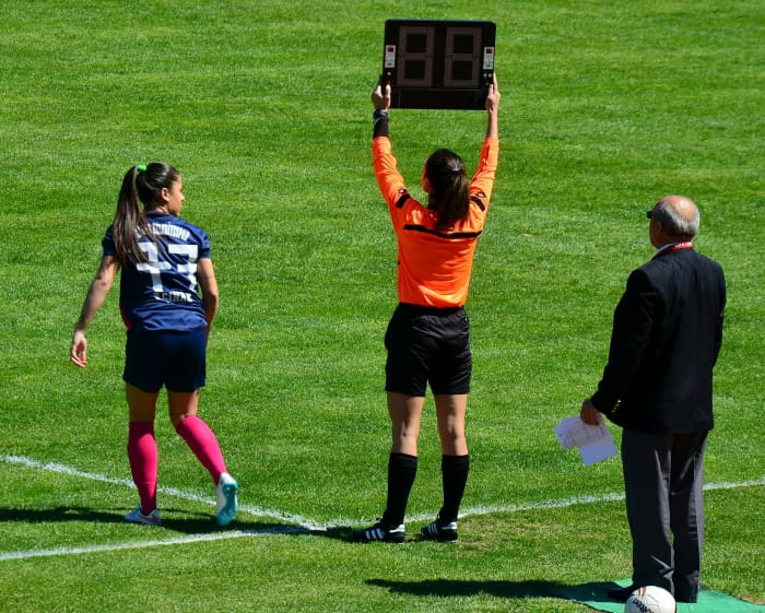 The match official will raise a board that shows the numbers of the players being substituted. At the end of each half, they'll use this board to show the added time.