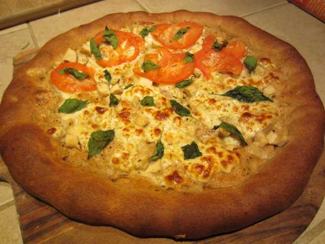 My whole wheat pizza base recipe with roasted garlic, mozzarella, leftover grilled chicken, basil, and some tomato