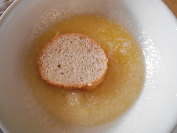 I like to melt my butter in a bowl and dip one side of the French bread rounds into it before placing on a baking sheet.