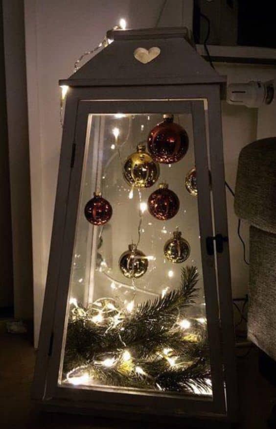 Here's a more abstract idea for a lantern: Dangle baubles from the top, and place greenery entwined with twinkle lights at the bottom.