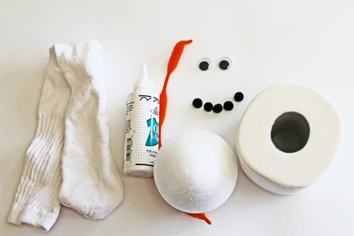 Here are the basic things you need to make this snowman: a tube sock, tacky glue (or hot glue gun with sticks), chenille stem, googly eyes, small pom poms, styrofoam ball and a roll of toilet paper.