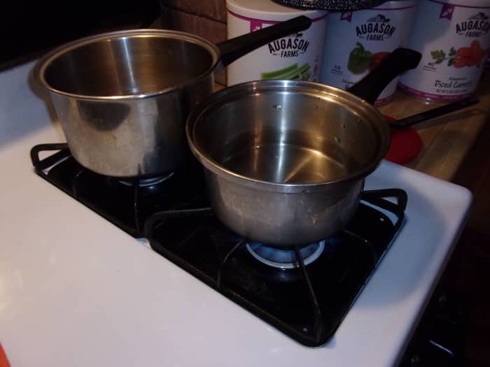 Put two cups of water in each pot and turn the burners on high. Put a lid on the pot you intend to use for noodles.