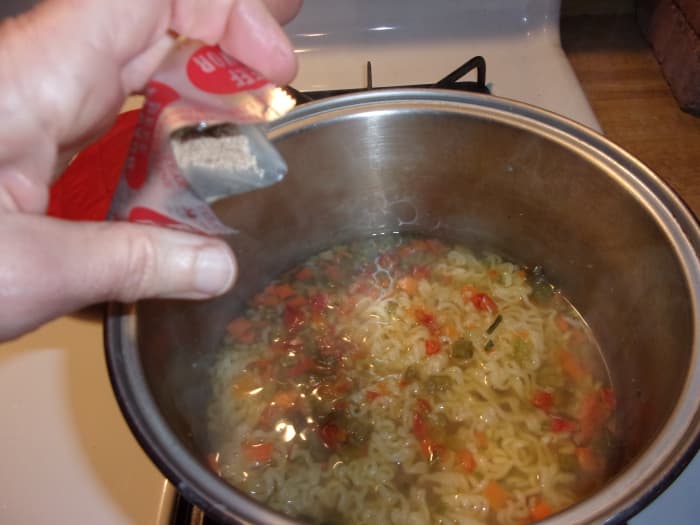 When your one minute timer goes off, turn off the heat under the noodles and veggies and add the flavor packet.