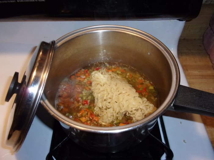 Add the noodles to the simmering veggies, cover the pot and let the veggies and noodles cook together. Set a timer for one minute.