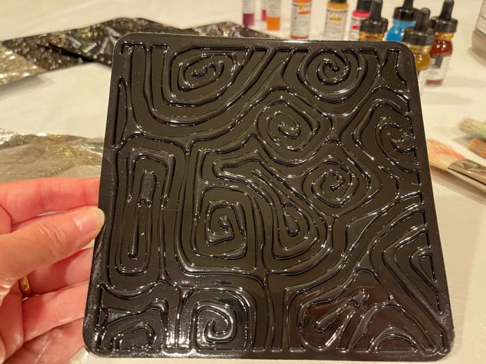A textured plastic plate that has a raised design works great for embossing foil.