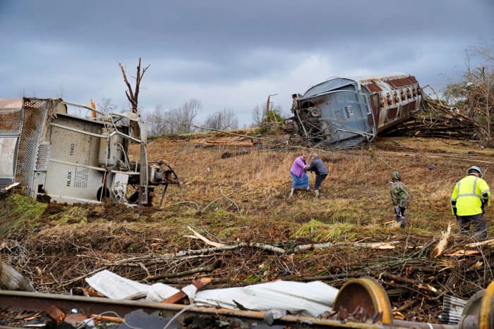 Local residents walk past the scene of a train derailment after a devastating outbreak of tornadoes ripped through several U.S. states in Earlington, Kentucky, U.S. December 11, 2021.