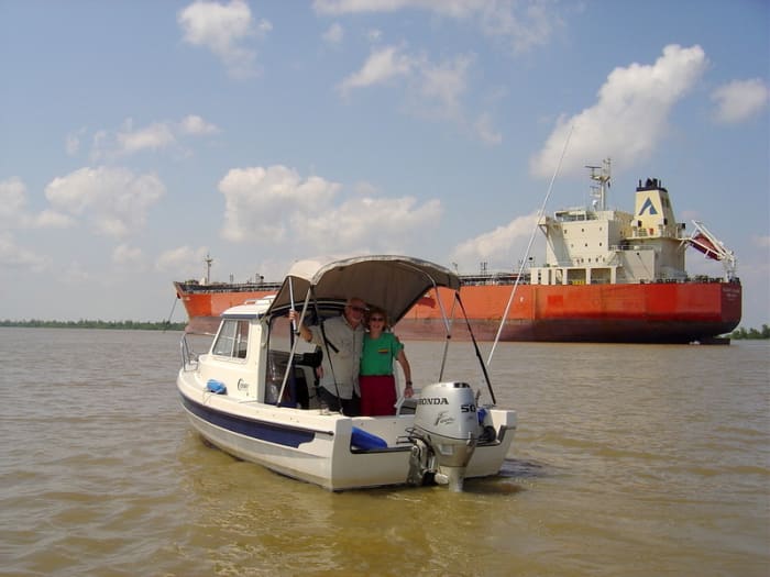 The author and her husband in "See-Saw," which is dwarfed by a huge red tanker south of Venice, LA, near Head of Passes on the Mississippi.