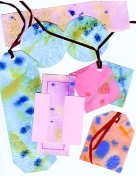 These are cut from painted paper, but the method is essentially the same. Cut a picture, punch a hole, add a ribbon.