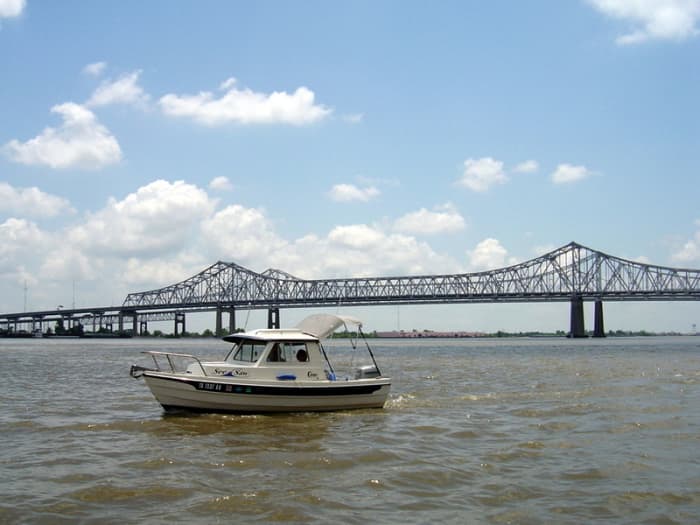 The small C-Dory "See-Saw" poses in front of the Crescent City Connection, the bridge over the Mississippi River that connects the two sides of New Orleans.