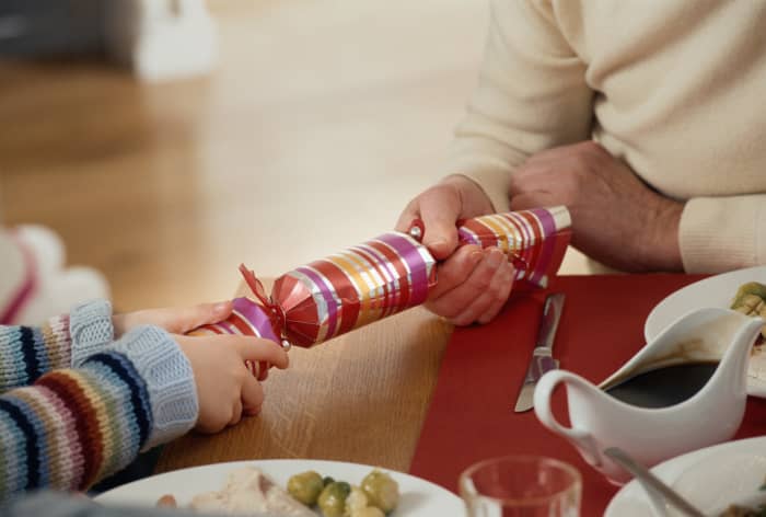 Each party-goer pulls on an end of the cracker to snap it open and reveal prizes like a hat or crown, papers with saying on them, and small gifts like plastic whistles and rings.