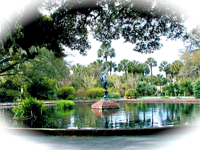 Diana of the Chase sculpture in in the center of the large reflecting pool that mirrors the sky, flowers and sculpture in a serene setting.