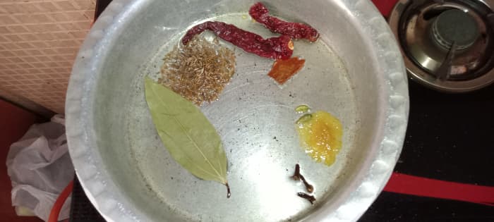 Heat 2 tablespoons oil and ghee each in a cooking pot. Add cumin seeds, dried red chillies, bay leaf, cinnamon, cloves, cardamom, and asafoetida.