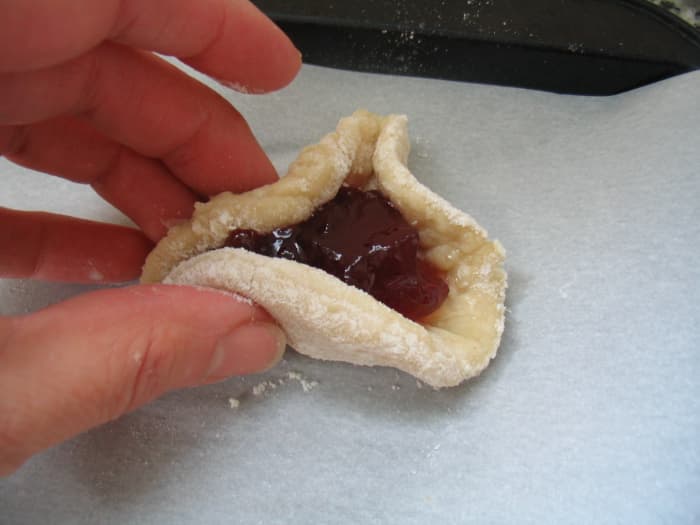 Fold the edges of the circles up to create triangles. Wet the outer edge of the dough, if necessary, to help it stick together.