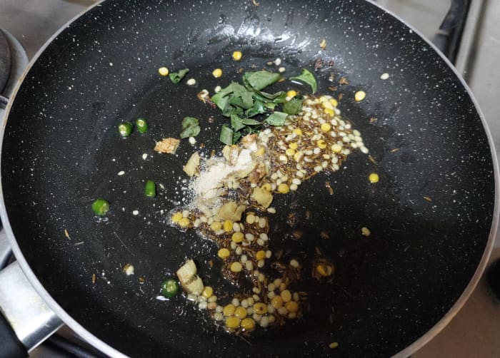 Add 1-2 springs of curry leaves, 1-2 chopped green chilies, 1 inch long chopped ginger, 1/2 teaspoon hing (asafoetida), fry for some seconds.